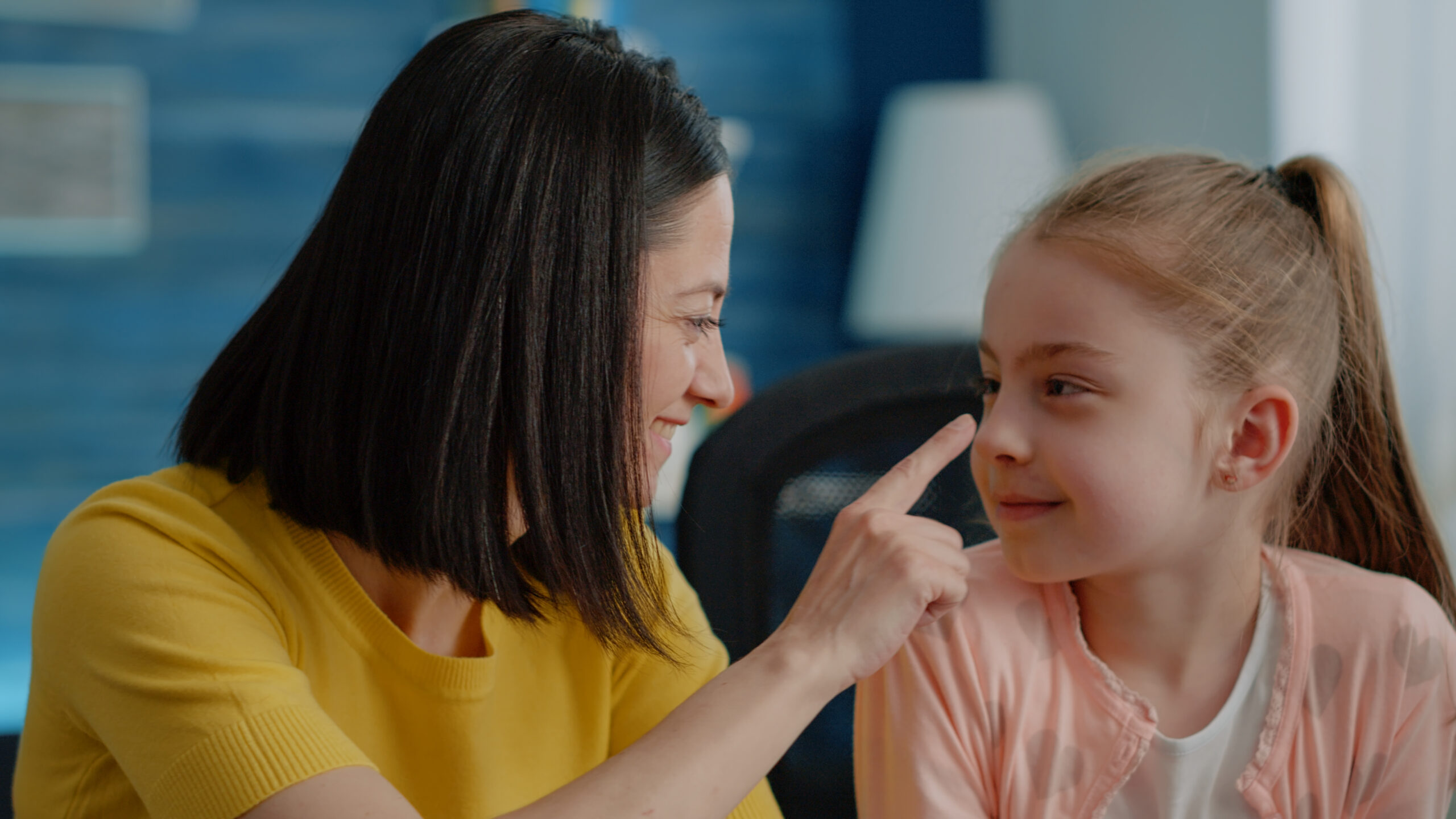 Close up of schoolgirl and mother doing homework together at desk. Portrait of parent and daughter preparing for online remote classes, looking at camera. Primary school pupil and adult