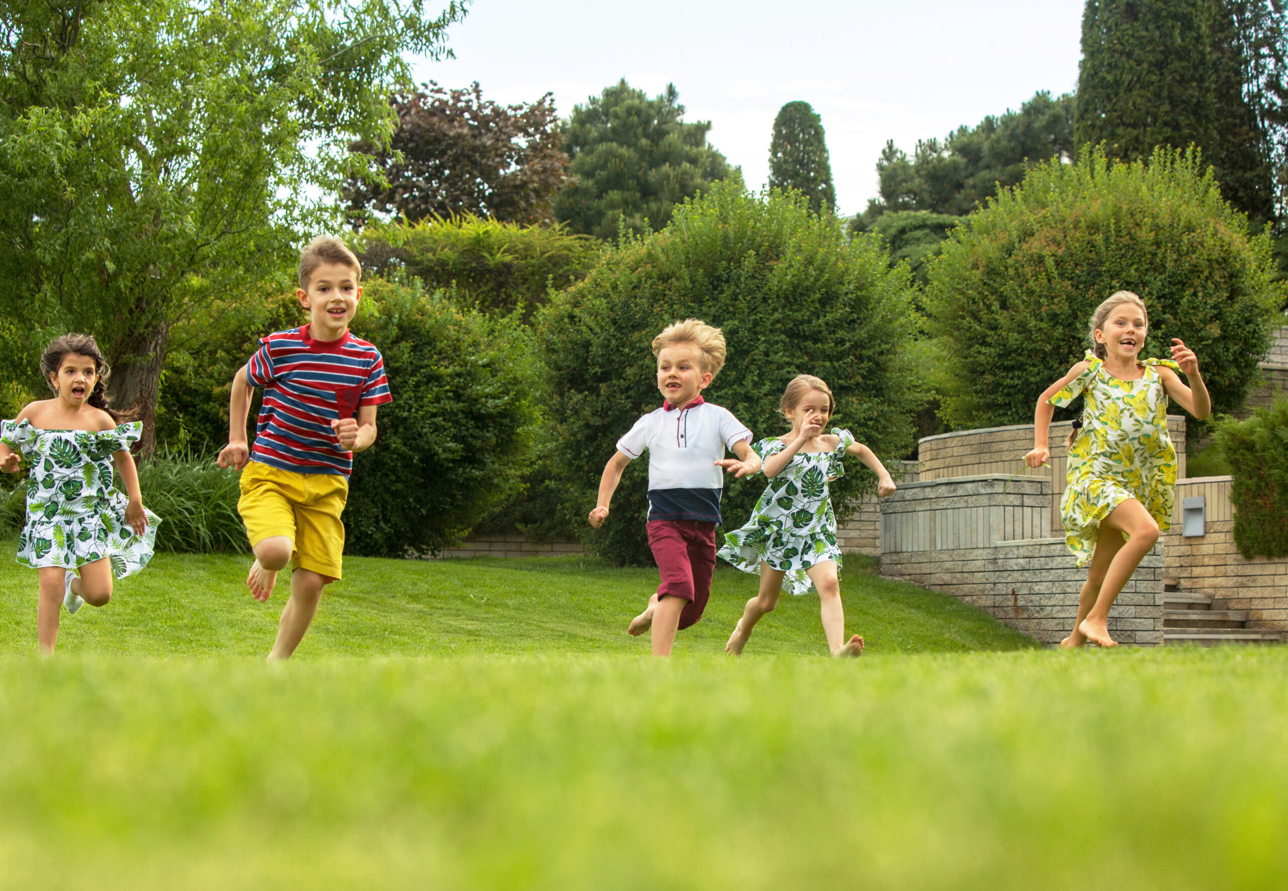 Funny starts. Kids fashion concept. The group of teen boys and girls running at park. Children colorful clothes, lifestyle, trendy colors concepts.