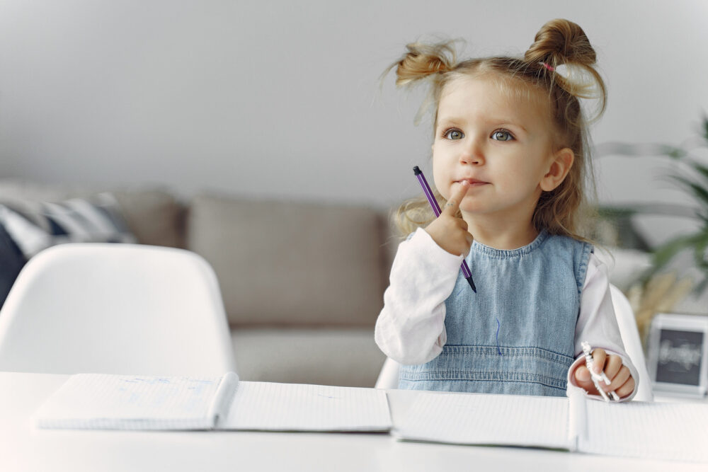 Child with a books. Girl sitting on a table. Kid in a class.