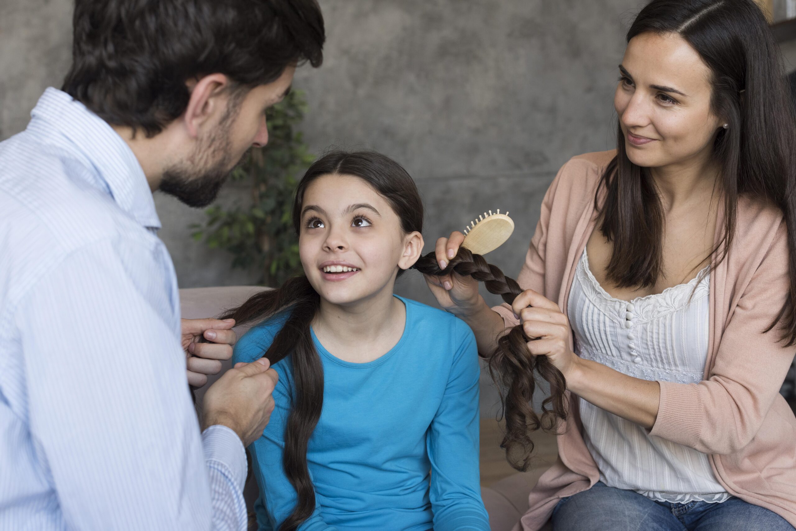 high-angle-parents-brushing-daughter-hair