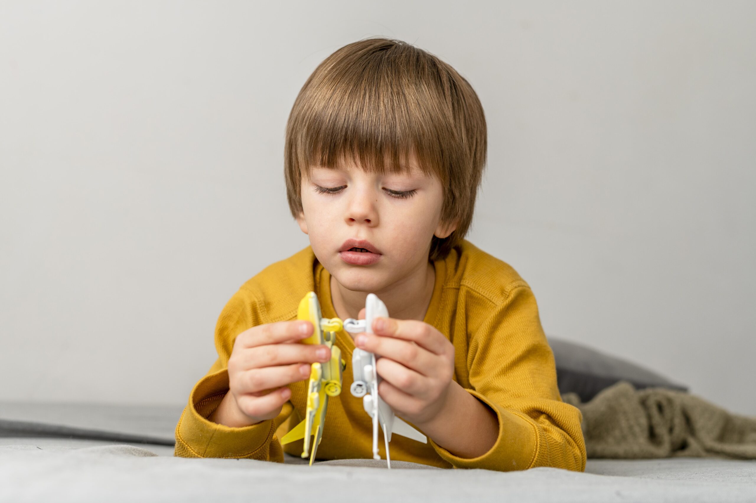front-view-boy-playing-with-airplane-figurines